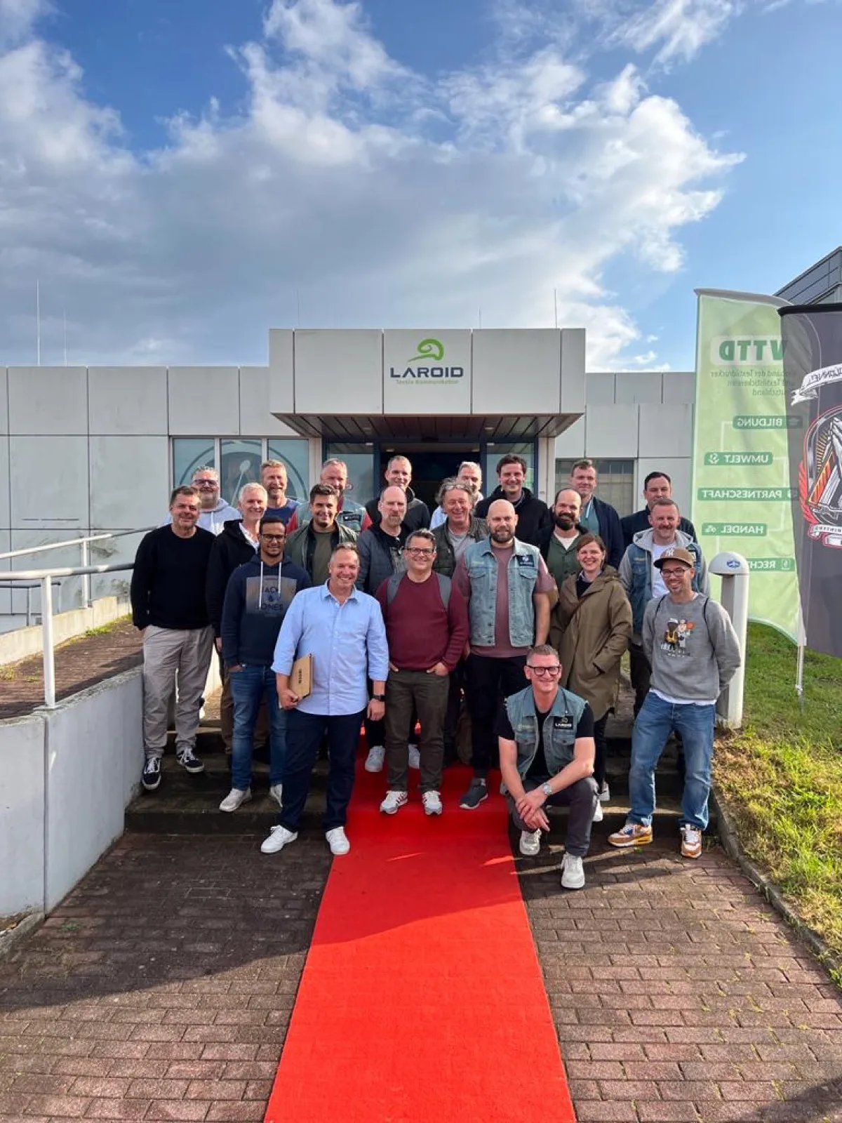 Gruppenfoto auf rotem Teppich vor einem Firmengebäude