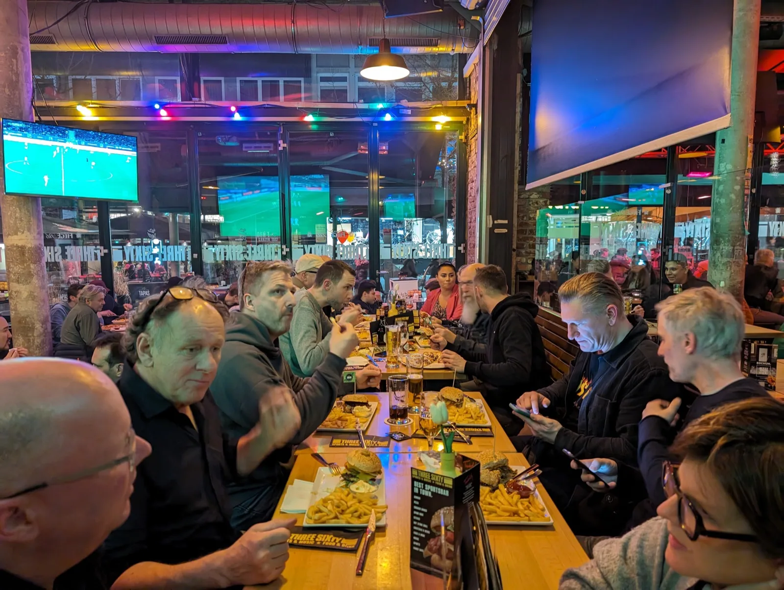 Lange Tafel in einer Sportsbar, Gäste vor Bildschirmen