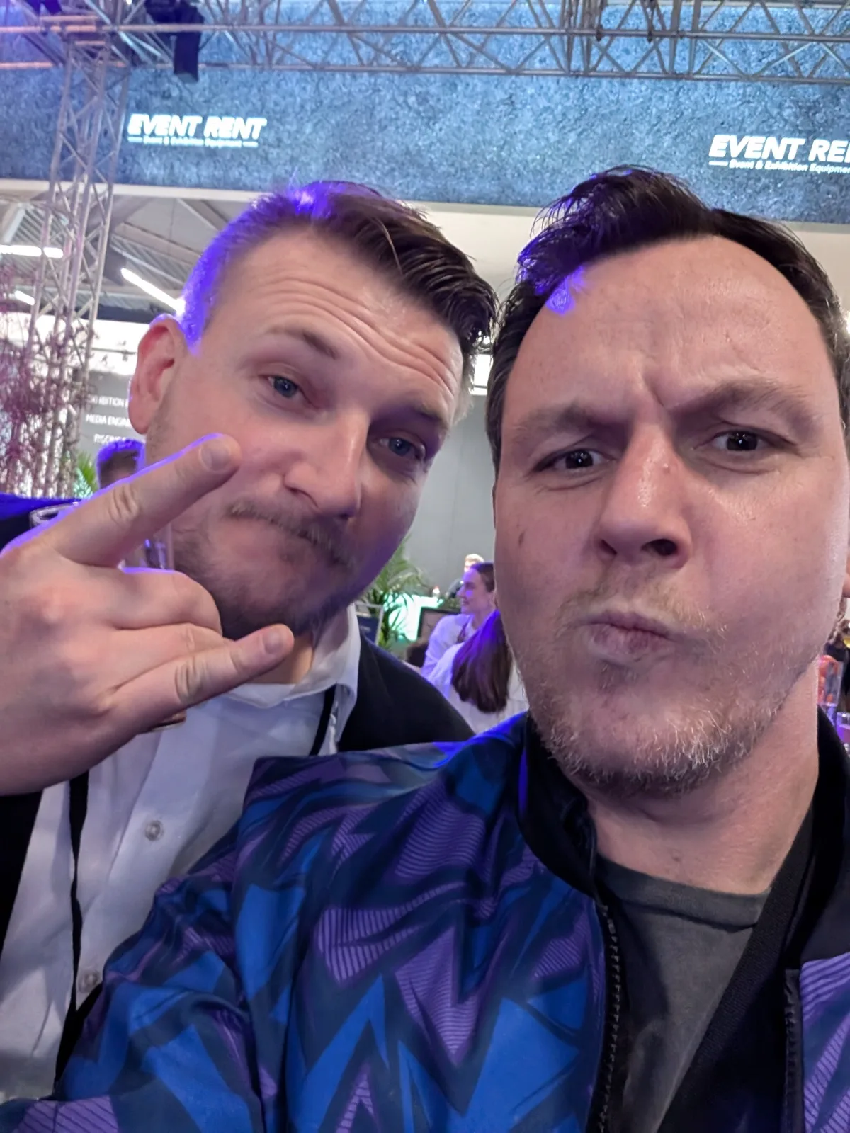 Selfie von zwei Männern vor einem Messestand