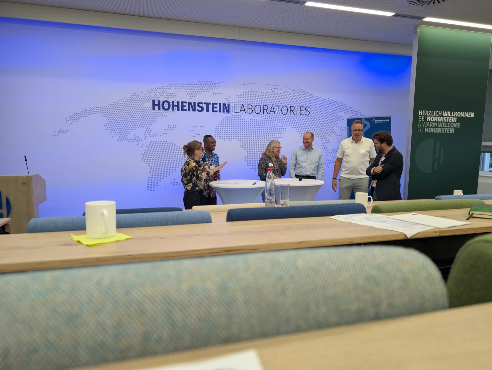 Konferenzraum eines Textillabors, Vortragende vor einer Weltkarte