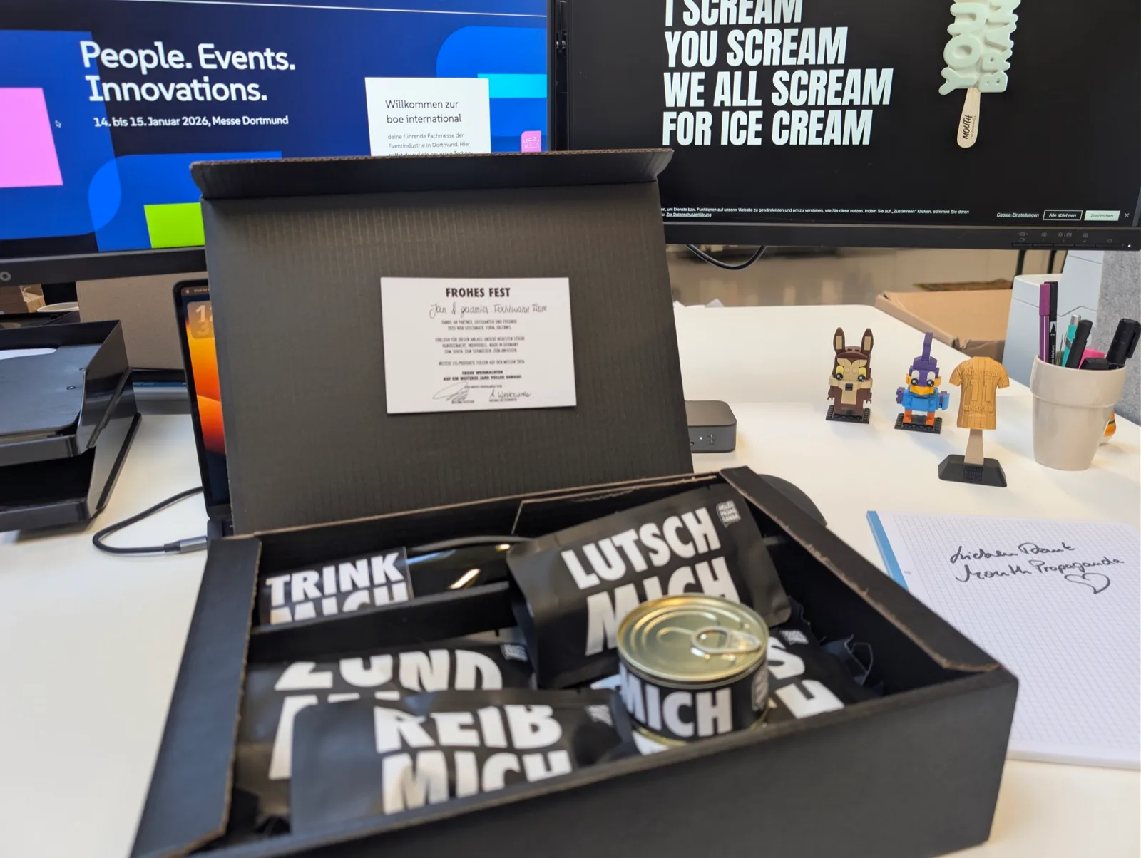 Offene Geschenkbox mit bedruckten Merch-Artikeln auf einem Schreibtisch
