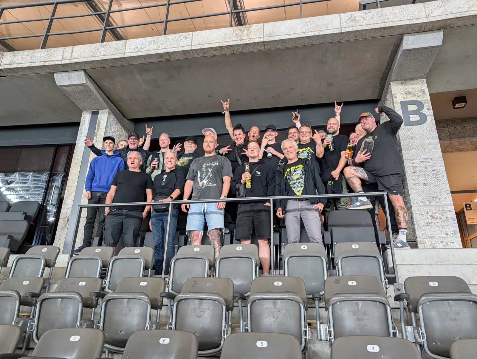 Gruppe auf einem Stadionbalkon, Arme in der Luft