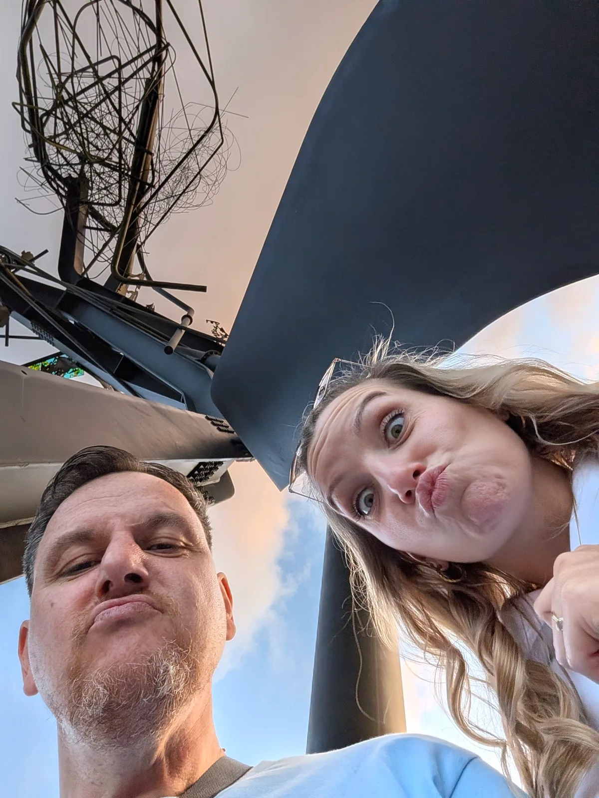 Selfie von zwei Personen von unten, dahinter ein ausgestelltes Fluggerät