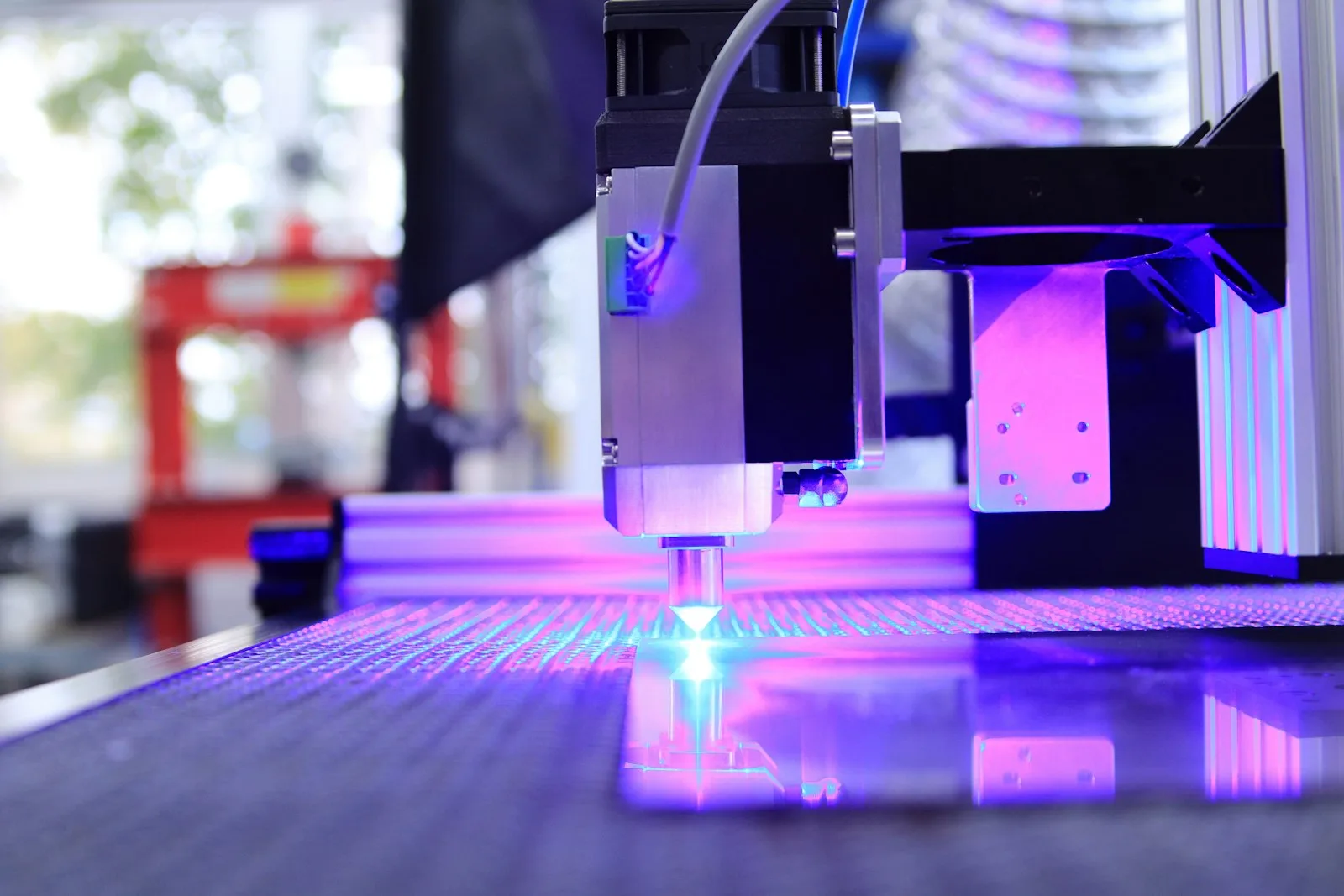 Laserkopf graviert ein Motiv, violettes Licht auf der Arbeitsfläche