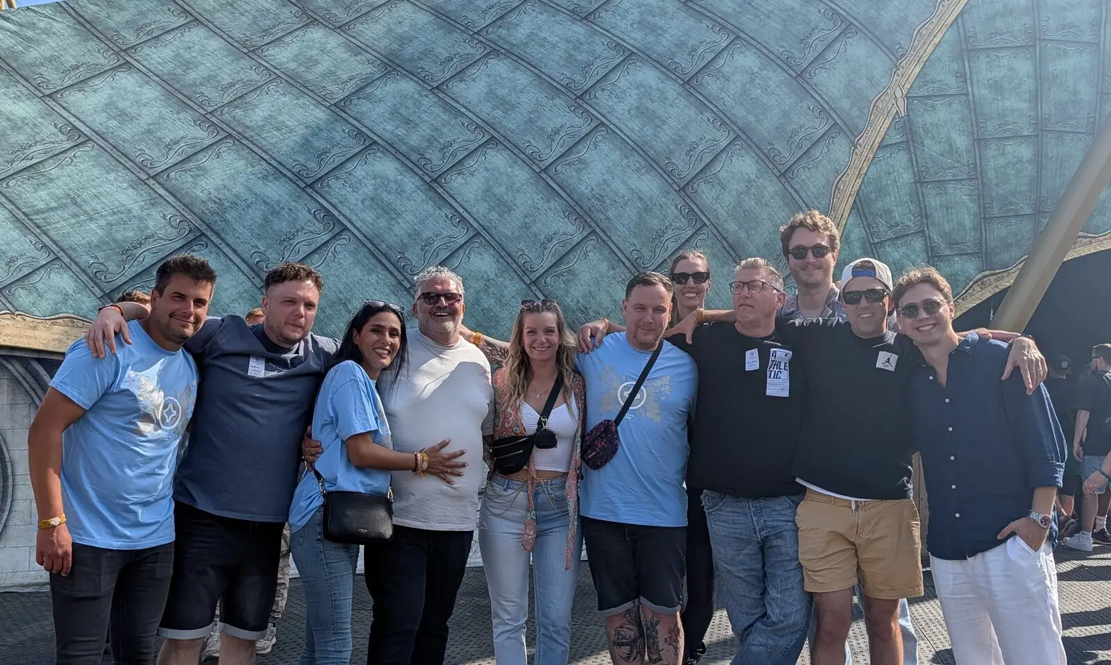 Photo de groupe à Tomorrowland : Jan Keur et d’autres invités bras dessus bras dessous devant un toit de tente bleu-vert