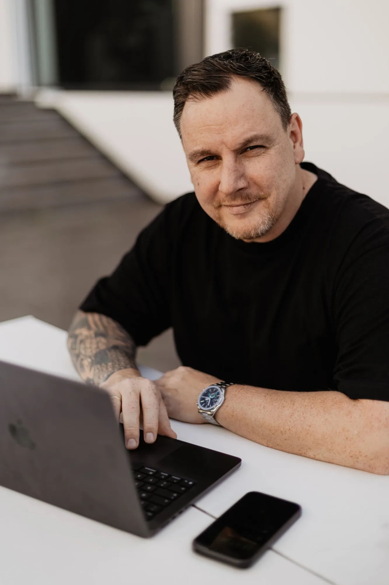 Jan Keur am Laptop, schwarzes Shirt, Blick in die Kamera