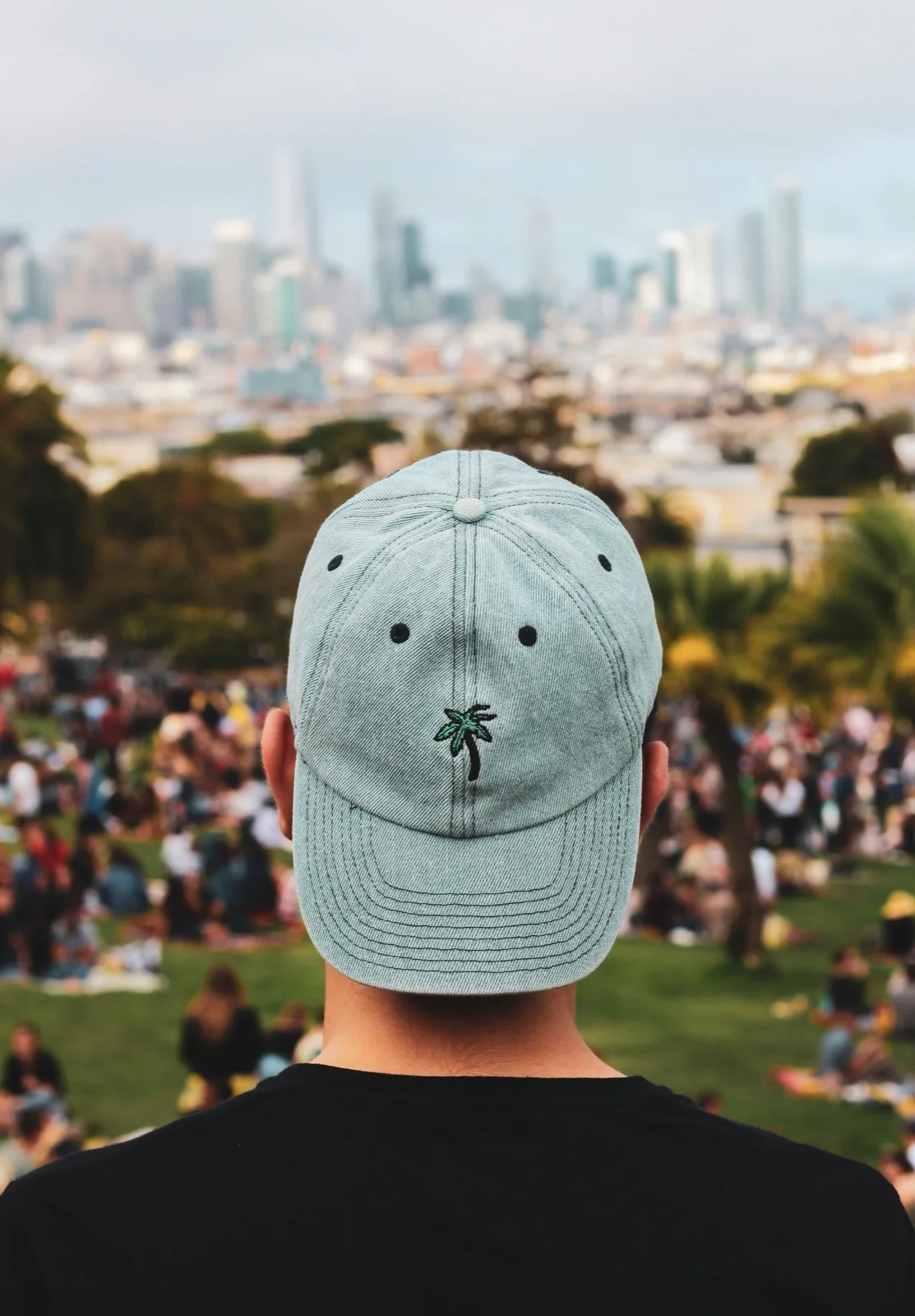 Graue Cap mit gestickter Palme, im Hintergrund Publikum