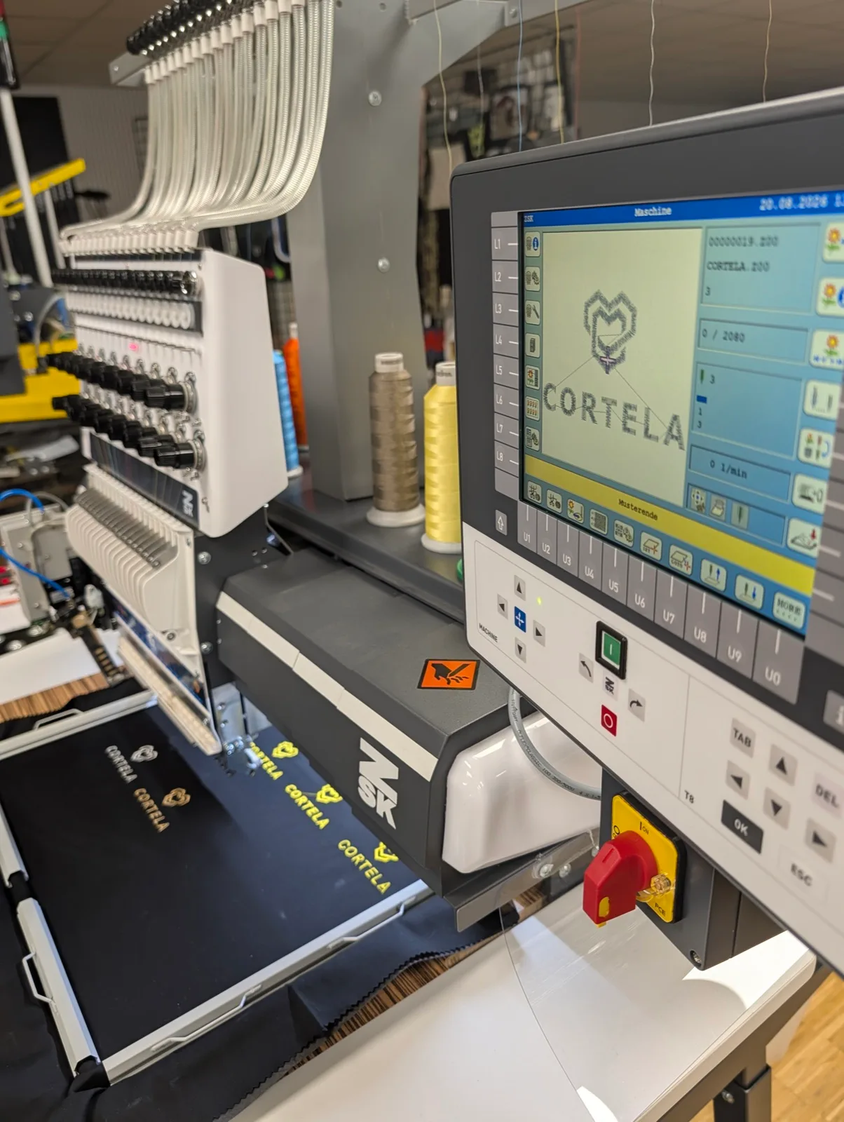 Stickmaschine mit Steuerungsdisplay, eingespanntes Textil unter dem Stickkopf